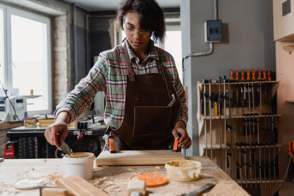 Image depicting a person wearing safety goggles and gloves while handling wood glue and thinning components