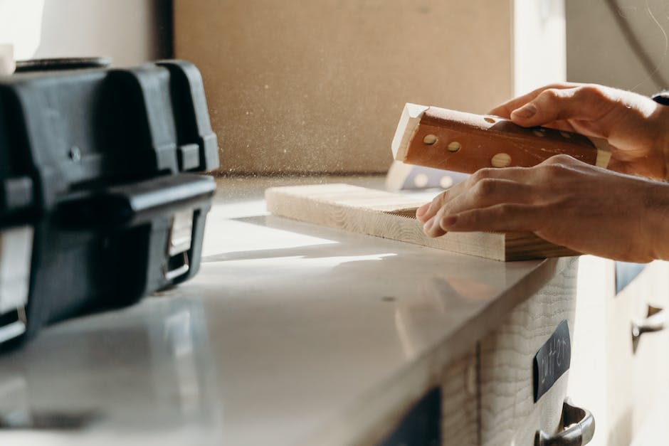 A person sanding wood with sandpaper, showing the proper technique and tools needed